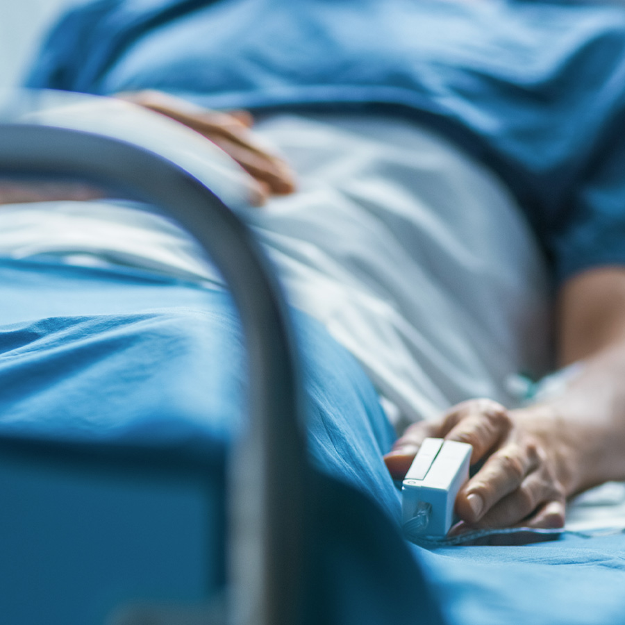 Patient laying in hospital bed with a finger-tip heart monitor